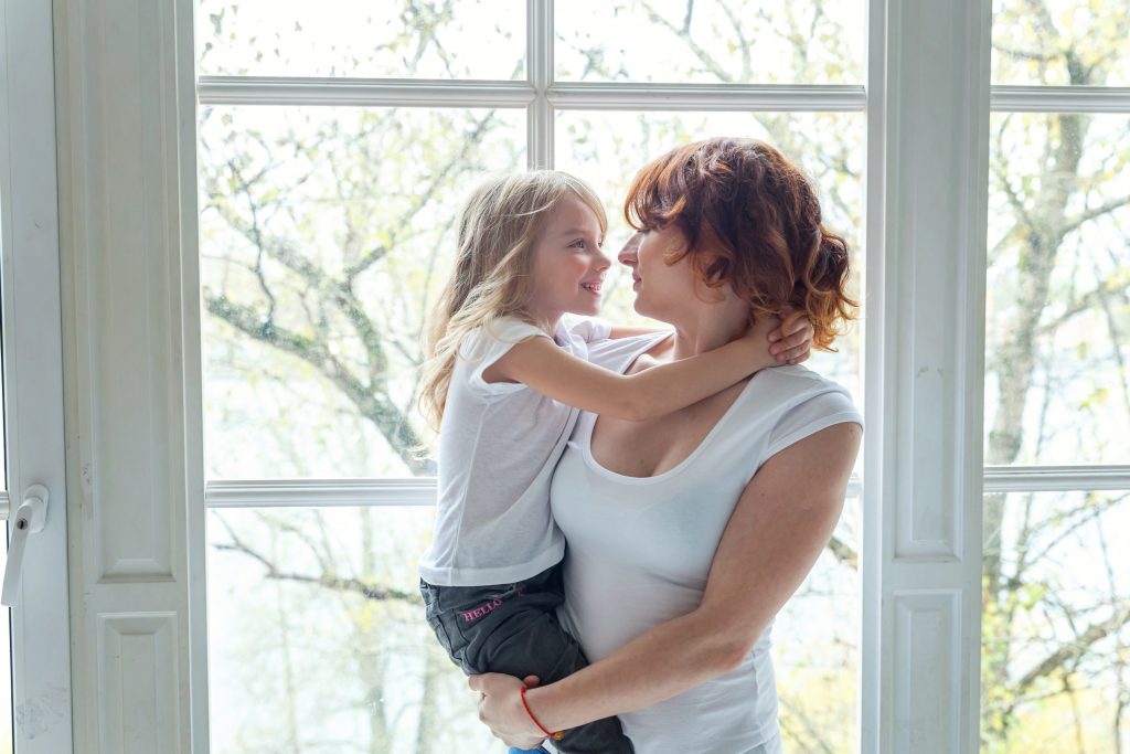 Woman holding child in front of window