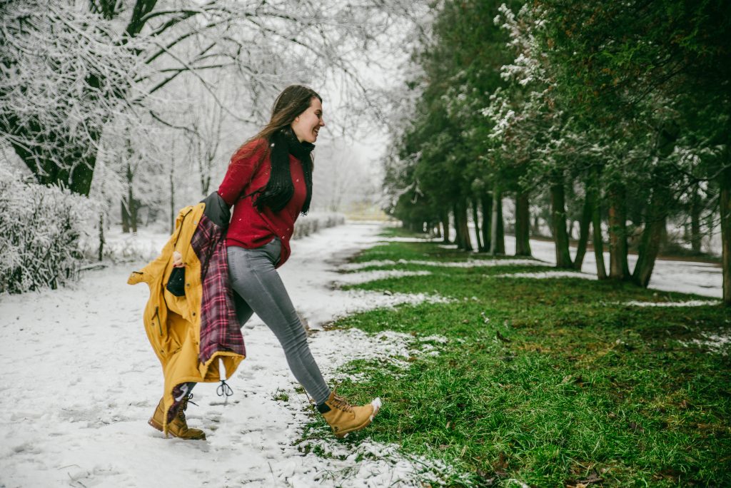 Girl walking out of snow into green trees