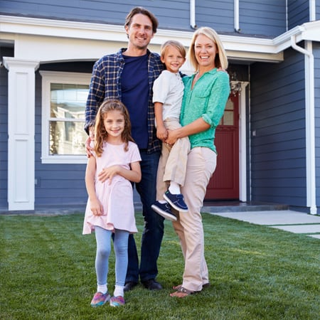 A happy family standing outside their home